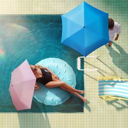 Knirps HeatShield Blonde Frau hält rosa Knirps HeatShield Regenschirm mit schwarzem Innen-Coating, ausgestattet mit UV-Schutz und Hitzereduzierung für optimalen Sonnenschutz.